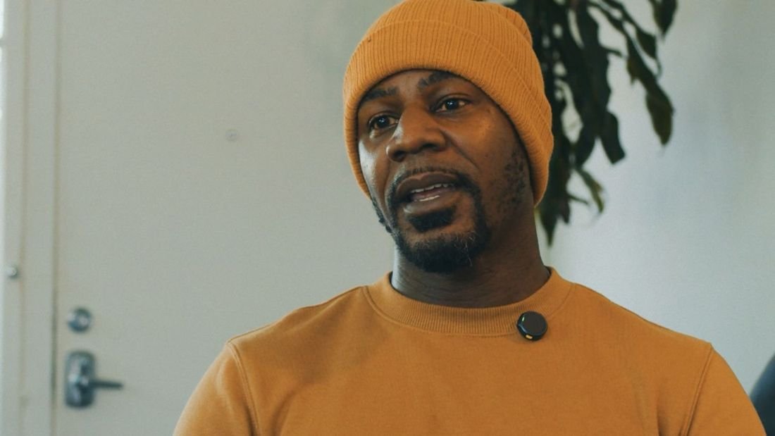 A man in an orange beanie speaking during an interview